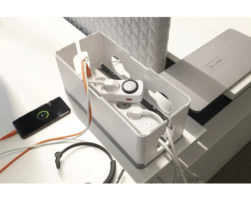 Kabellåda med grenuttag, timer, hörlurar och smartphone på ett bord.