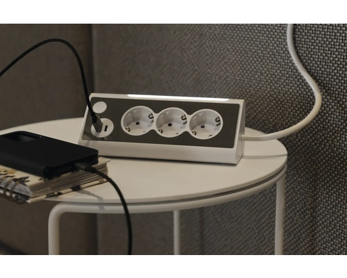 Grenuttag med USB-port på ett bord med laddningskabel