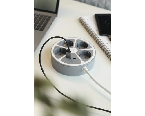 Runt grenuttag med flera anslutningar och USB-port på ett skrivbord.