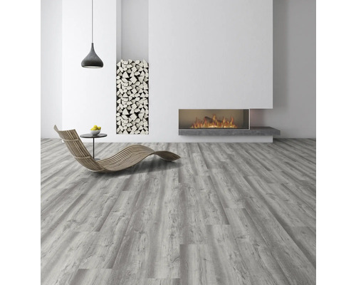 Ljust rum med laminatgolv, öppen spis, vedstapel och schäslong