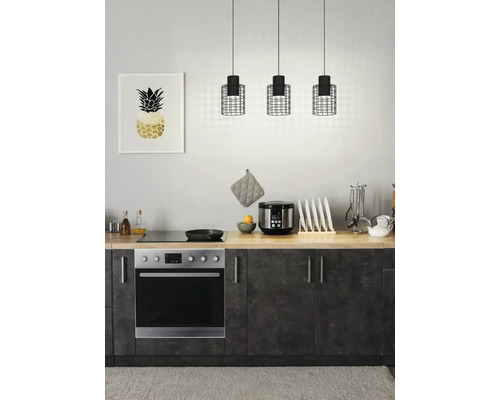 Köksscen med tre hänglampor ovanför en bänkskiva med apparater och en ram med en ananasbild