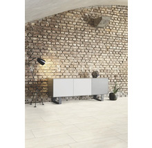 Vardagsrum med tegelvägg, byrå, golvlampa och golvplattor