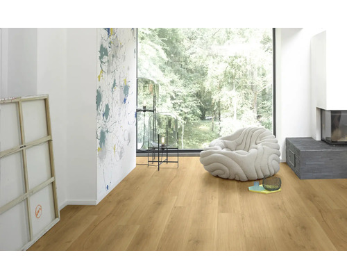 Ljust rum med laminatgolv, fåtölj och öppen spis