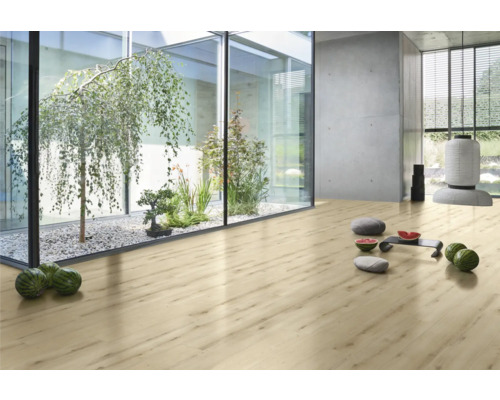 Ljust rum med laminatgolv, inomhusträdgård med träd och växter bakom glas