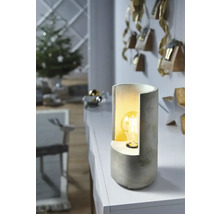 Bordslampa i betong på ett bord i ett vardagsrum med juldekorationer.