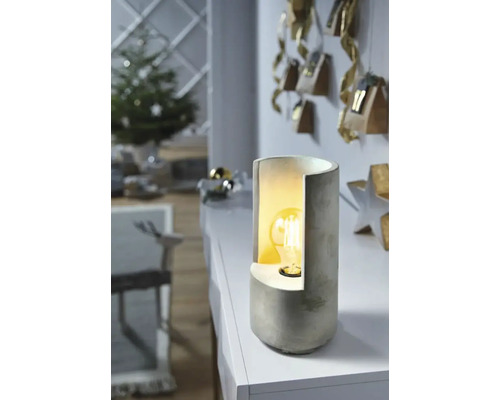 Bordslampa i betong på ett bord i ett vardagsrum med juldekorationer.