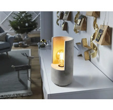 Dekorativ bordslampa av betong bredvid en adventskalender i ett vardagsrum.