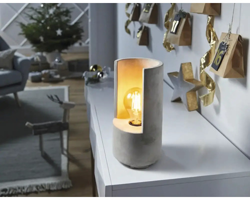 Dekorativ bordslampa av betong bredvid en adventskalender i ett vardagsrum.