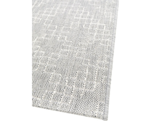 Detaljvy av en ljus matta med geometriskt mönster.