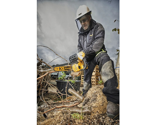 Man med skyddshjälm och ansiktsskydd sågar grenar med en motorsåg.