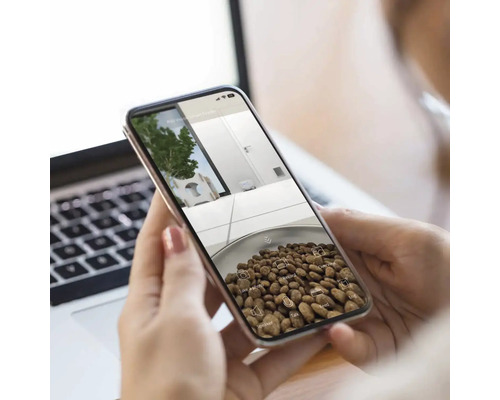 Kvinna håller en smarttelefon med Augmented Reality-app som visar kaffebönor och en växt utomhus