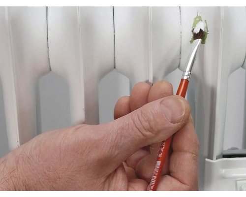 En hand håller en pensel för att måla ett element.