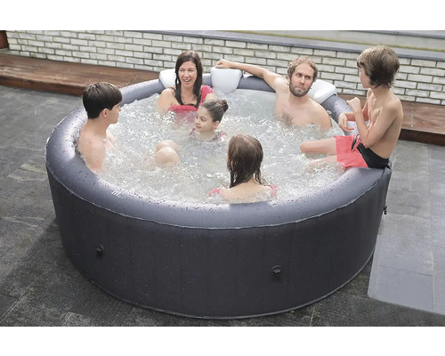 Familj kopplar av i uppblåsbar bubbelpool i trädgården