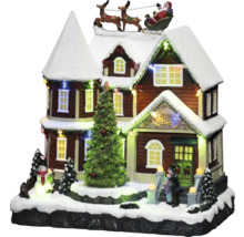 Belyst julhus med jultomten i släde som dekoration