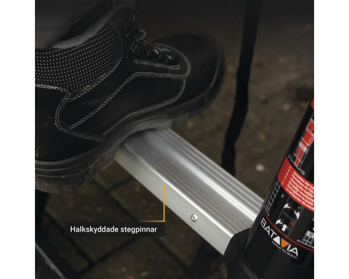 Detaljbild av ett steg med halkskyddsbeläggning och en arbetssko som står på det.