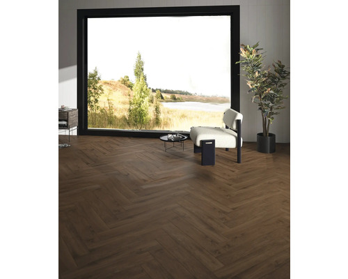 Interiör med trägolv i fiskbensmönster, fåtölj, bord och stort fönster