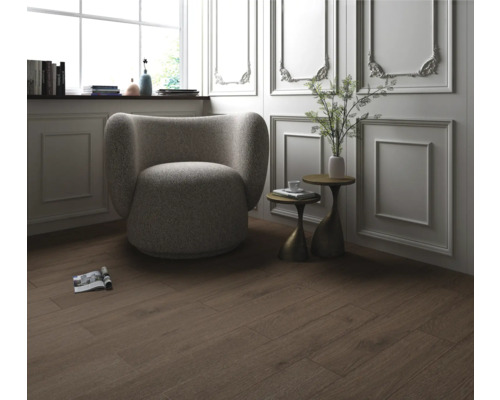 Interiör med trägolv, fåtölj och sidobord.