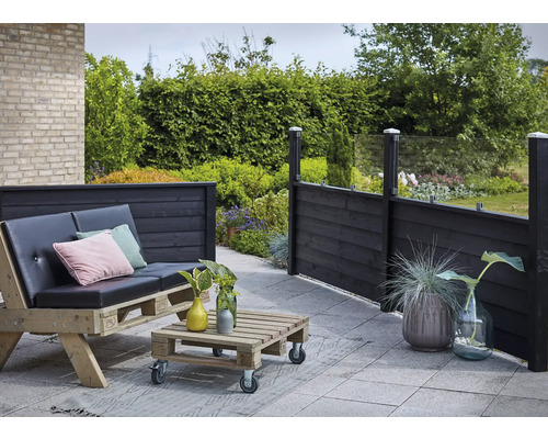 Uteplats med träterrass, pallmöbler och trästaket med glaselement