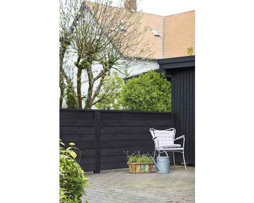 Sittplats i trädgården med trästaket, stol, vattenkanna och växtkorg