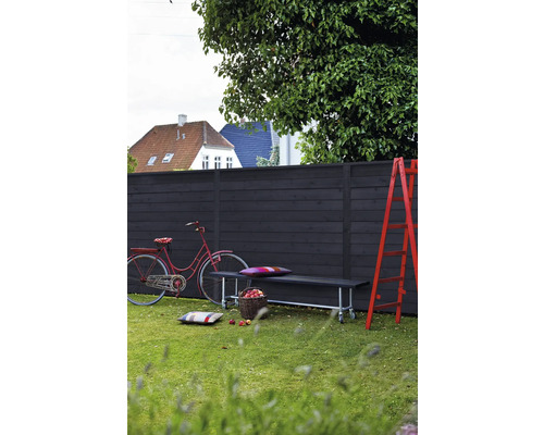 Trädgårdsscen med trästaket, bänk, stege och cykel