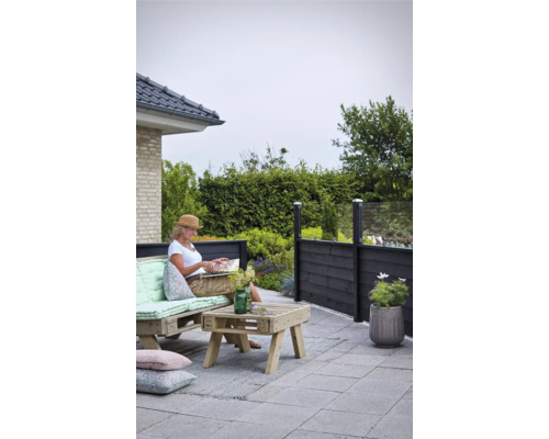 Terrassscen med spjälstaket, pallmöbler och en kvinna som läser en bok