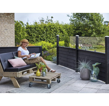 Terrassscen med kvinna på pallsoffa, pallbord och insynsskydd