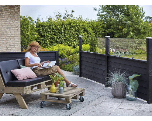 Terrassscen med kvinna på pallsoffa, pallbord och insynsskydd