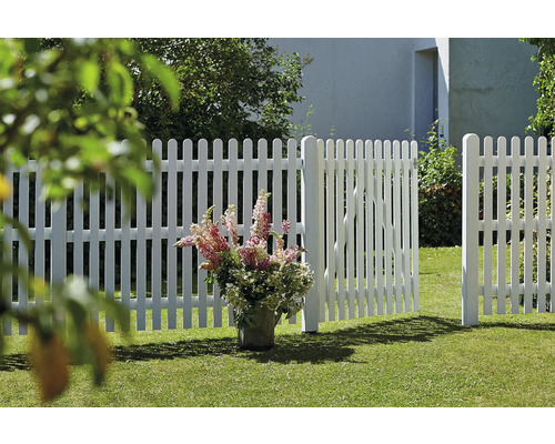 Vitt staket med öppen trädgårdsport på en gräsmatta