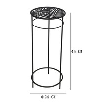 Rund blomstativ i metall med bladmönster på hyllan, 45 centimeter hög och 24 centimeter i diameter.